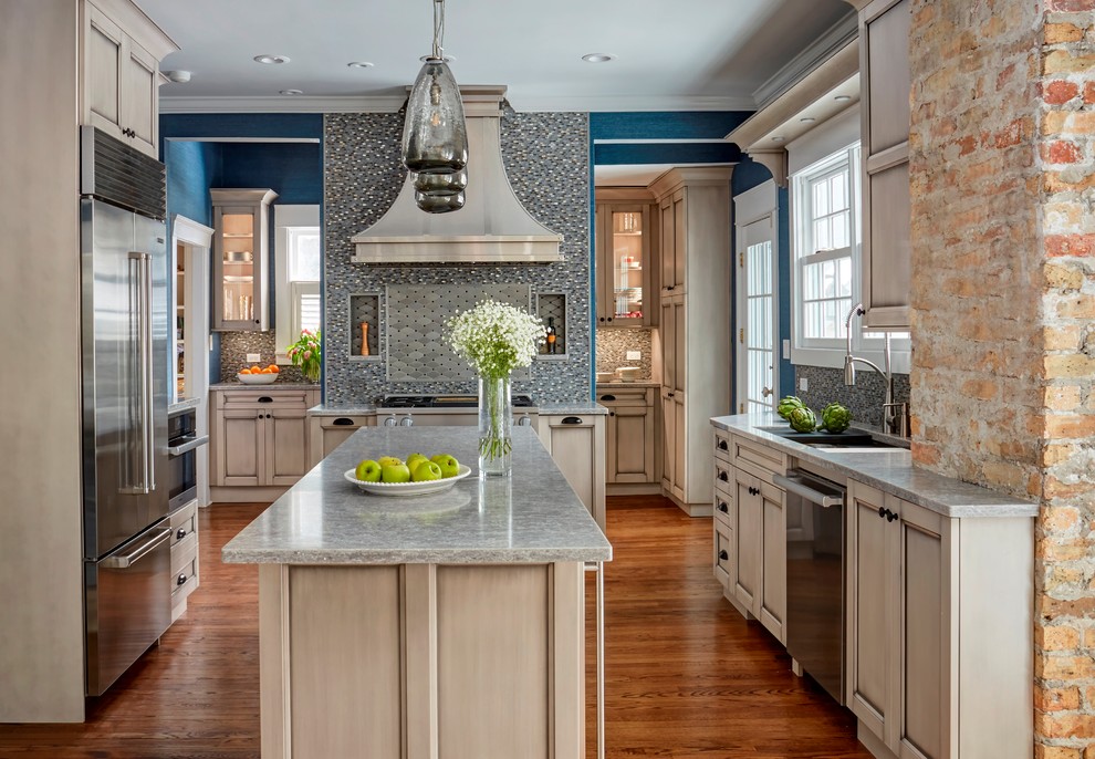This is an example of a large traditional kitchen in Chicago with recessed-panel cabinets, engineered stone countertops, mosaic tiled splashback, stainless steel appliances, medium hardwood flooring, an island, a submerged sink, beige cabinets and multi-coloured splashback.