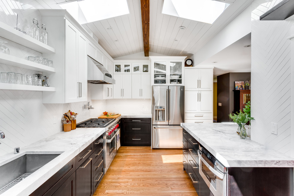 Photo of a traditional u-shaped enclosed kitchen in Seattle with a submerged sink, shaker cabinets, white cabinets, white splashback, stainless steel appliances, medium hardwood flooring, a breakfast bar and quartz worktops.