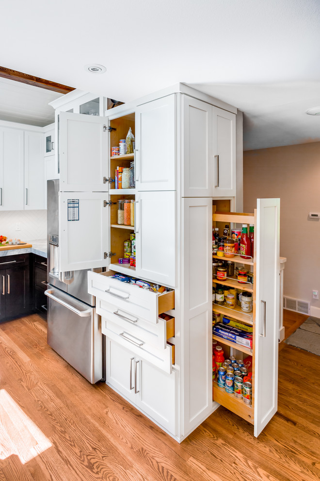 Transitional medium tone wood floor kitchen photo in Seattle with shaker cabinets, white cabinets and stainless steel appliances