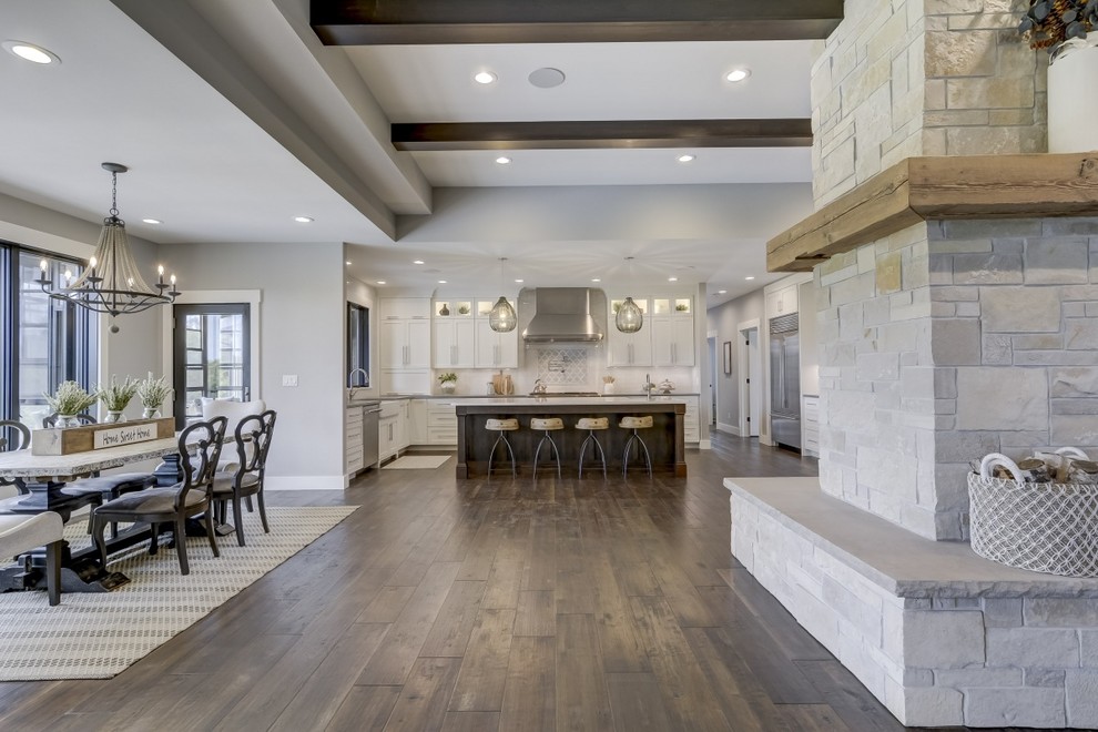Design ideas for a large farmhouse u-shaped open plan kitchen in Chicago with a belfast sink, recessed-panel cabinets, white cabinets, engineered stone countertops, white splashback, metro tiled splashback, stainless steel appliances, porcelain flooring, an island, brown floors and white worktops.