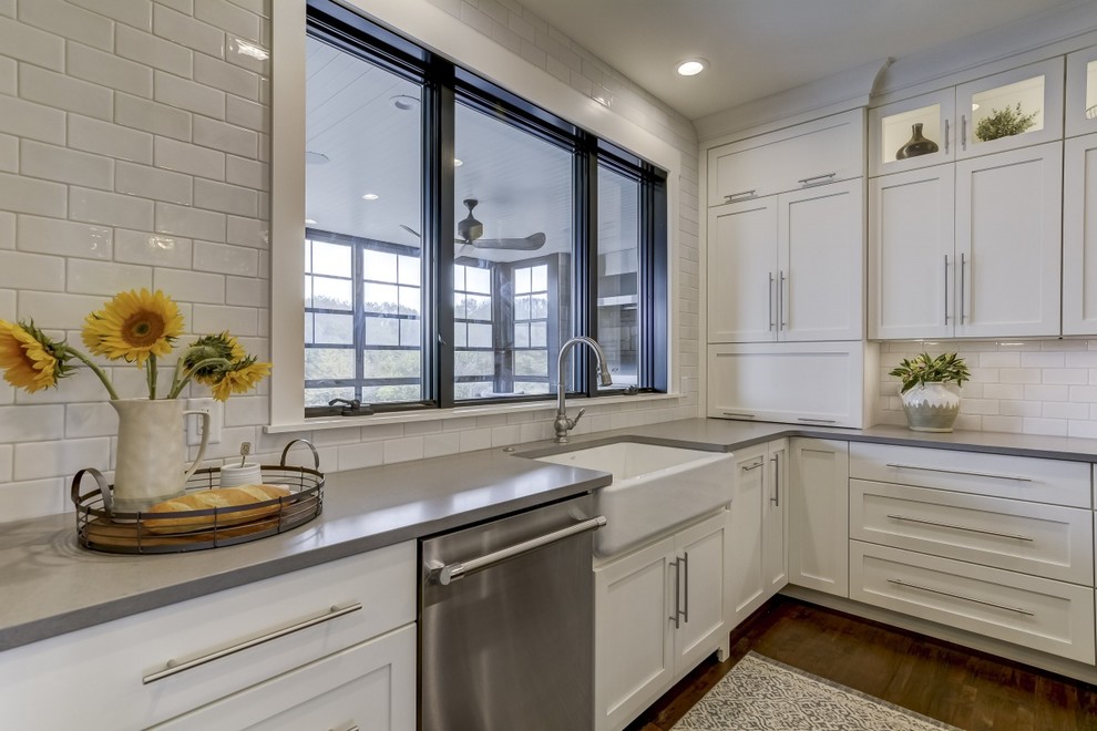 Example of a large farmhouse u-shaped porcelain tile and brown floor open concept kitchen design in Chicago with a farmhouse sink, recessed-panel cabinets, white cabinets, quartz countertops, white backsplash, subway tile backsplash, stainless steel appliances, an island and white countertops