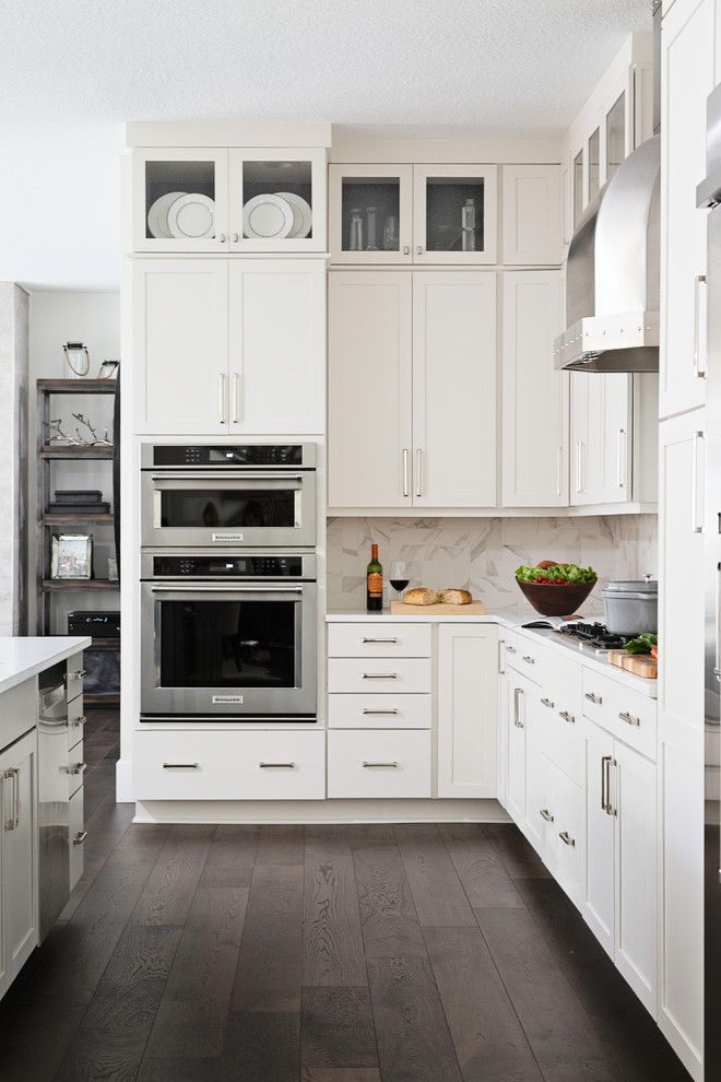 Klassisk inredning av ett mellanstort vit vitt kök, med en undermonterad diskho, skåp i shakerstil, vita skåp, bänkskiva i koppar, vitt stänkskydd, stänkskydd i sten, rostfria vitvaror, mörkt trägolv, en köksö och brunt golv