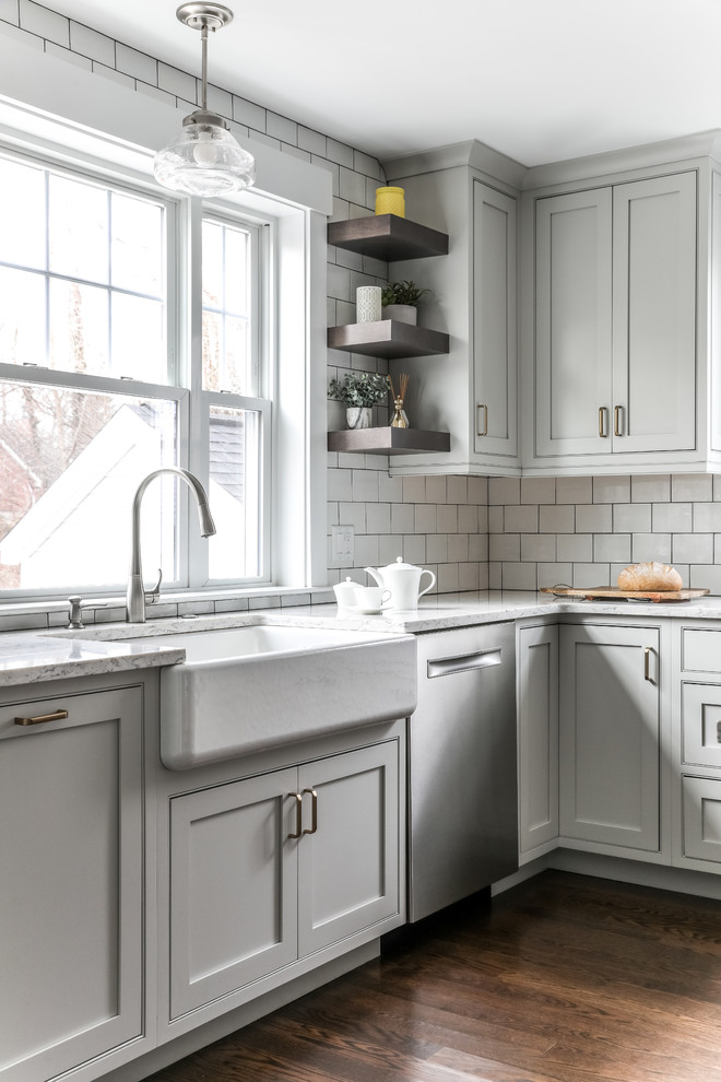 Idéer för att renovera ett vintage grå grått kök, med en rustik diskho, luckor med profilerade fronter, vita skåp, bänkskiva i kvarts, vitt stänkskydd, stänkskydd i tunnelbanekakel, rostfria vitvaror, mellanmörkt trägolv, en köksö och brunt golv