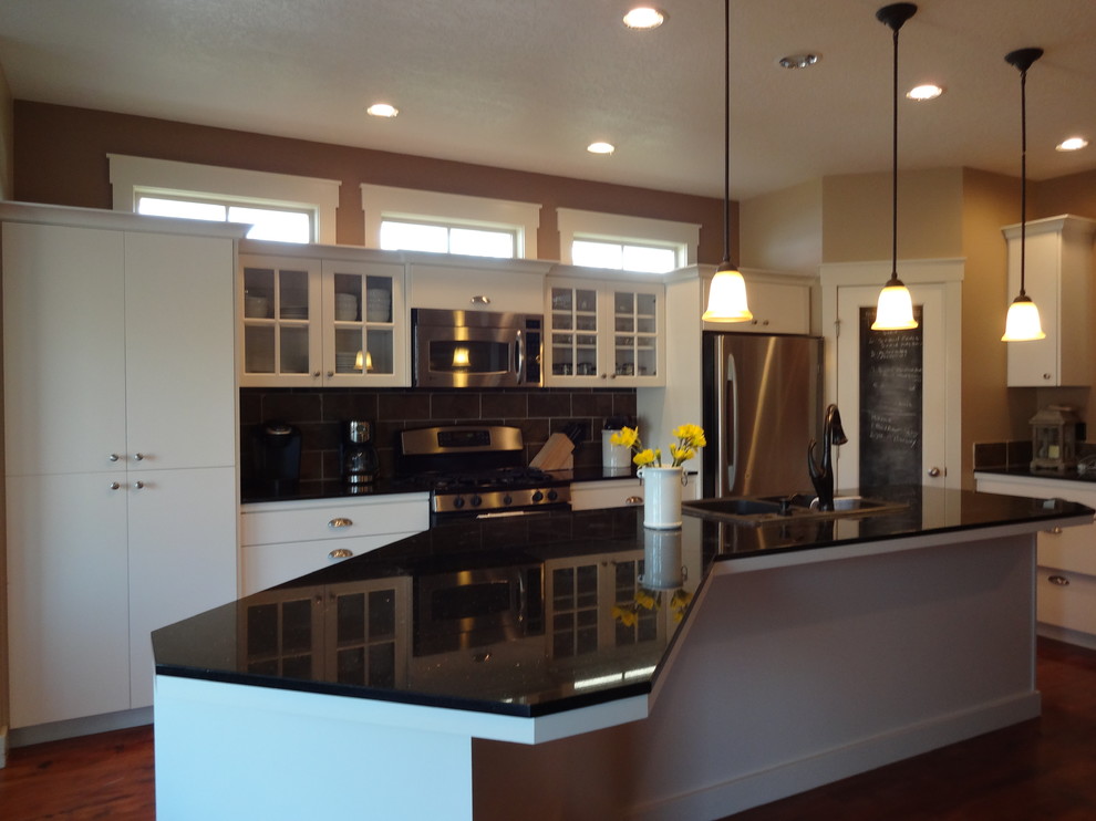 This is an example of a large country galley kitchen/diner in Boise with a double-bowl sink, flat-panel cabinets, white cabinets, granite worktops, grey splashback, metro tiled splashback, stainless steel appliances and medium hardwood flooring.