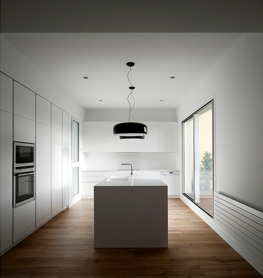 Foto de cocina minimalista grande abierta con armarios con paneles lisos, puertas de armario blancas, electrodomésticos con paneles, suelo de madera en tonos medios y una isla