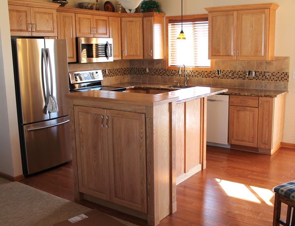 Eat-in kitchen - small traditional l-shaped medium tone wood floor eat-in kitchen idea in Other with an undermount sink, raised-panel cabinets, light wood cabinets, granite countertops, multicolored backsplash, mosaic tile backsplash, stainless steel appliances and an island