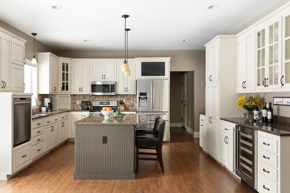 This is an example of a medium sized classic u-shaped kitchen in Minneapolis with a submerged sink, raised-panel cabinets, white cabinets, granite worktops, brown splashback, stone tiled splashback, stainless steel appliances, laminate floors, an island, brown floors and brown worktops.