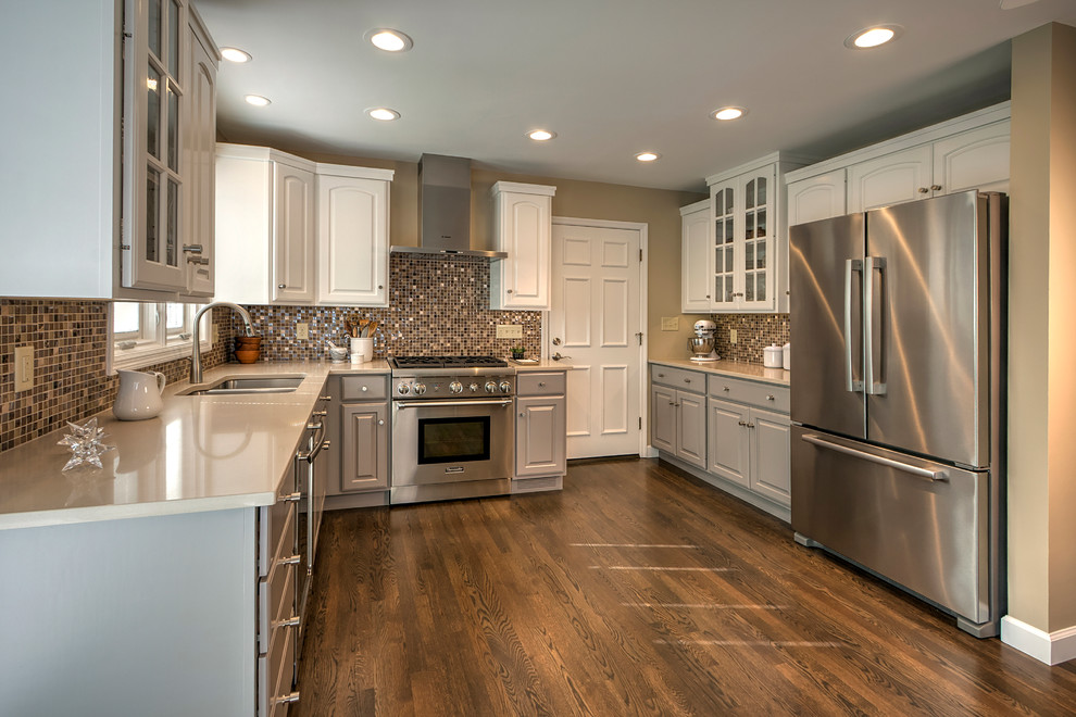 Example of a mid-sized trendy u-shaped medium tone wood floor kitchen pantry design in St Louis with an undermount sink, recessed-panel cabinets, gray cabinets, quartzite countertops, metallic backsplash, glass tile backsplash, stainless steel appliances and no island