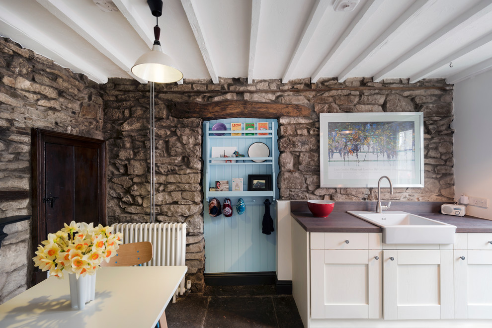 This is an example of a rustic single-wall kitchen/diner in Other with a belfast sink, shaker cabinets, white cabinets, wood worktops, stone slab splashback and no island.