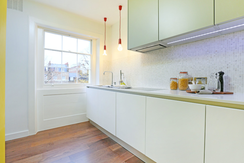 Photo of a small contemporary l-shaped enclosed kitchen in London with flat-panel cabinets, stone tiled splashback and no island.