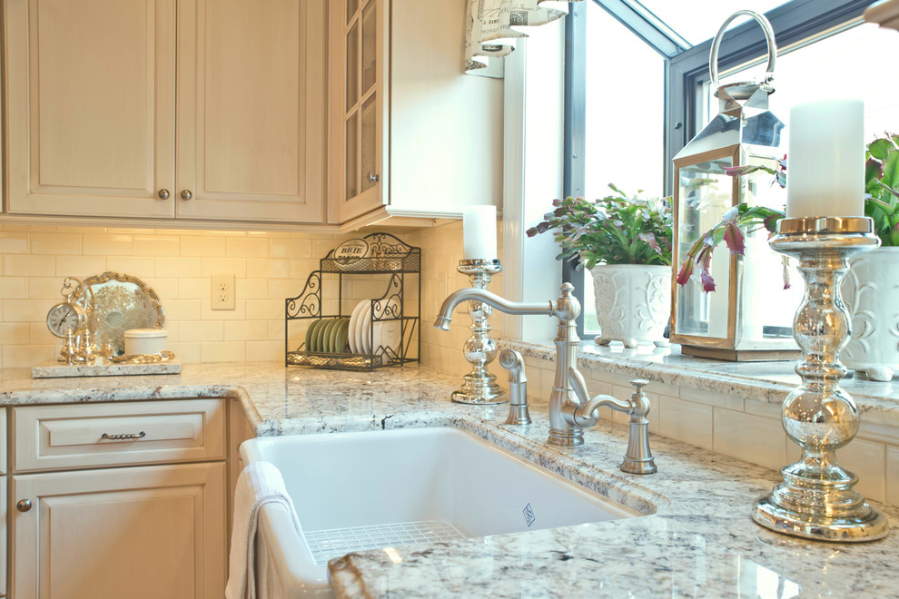Mid-sized elegant l-shaped medium tone wood floor and beige floor eat-in kitchen photo in New York with a farmhouse sink, raised-panel cabinets, white cabinets, granite countertops, white backsplash, subway tile backsplash, stainless steel appliances and an island