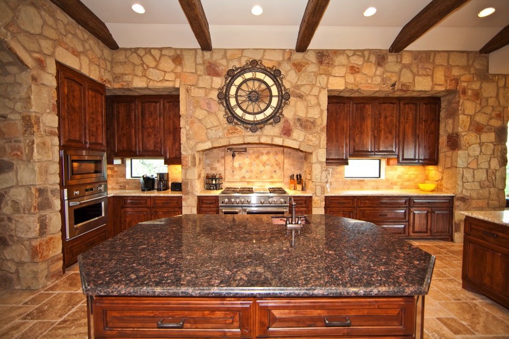 Example of a tuscan u-shaped limestone floor kitchen design in Austin with a farmhouse sink, raised-panel cabinets, dark wood cabinets, granite countertops, beige backsplash, ceramic backsplash, stainless steel appliances and an island