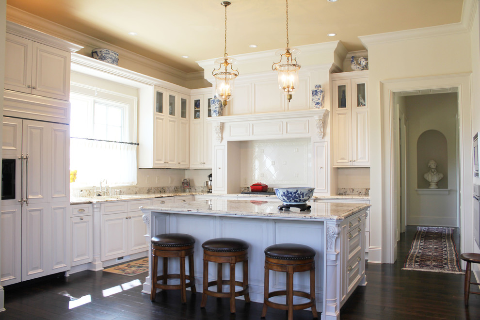 Example of a classic u-shaped dark wood floor eat-in kitchen design in Indianapolis with raised-panel cabinets, white cabinets, white backsplash, an undermount sink, granite countertops, paneled appliances and an island