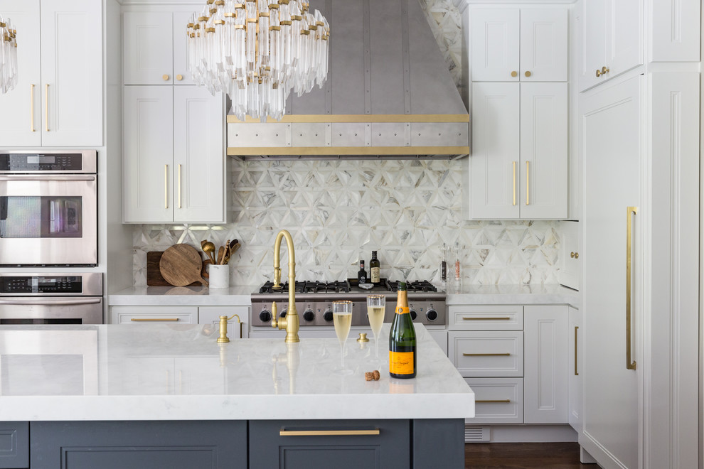 Inspiration for a transitional l-shaped medium tone wood floor and brown floor kitchen remodel in San Francisco with recessed-panel cabinets, white cabinets, white backsplash, stainless steel appliances, an island and white countertops