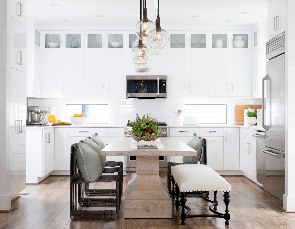 This is an example of a nautical u-shaped kitchen/diner in DC Metro with flat-panel cabinets, white cabinets, white splashback, metro tiled splashback, stainless steel appliances and dark hardwood flooring.