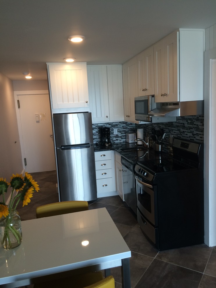 Example of a small beach style l-shaped eat-in kitchen design in Other with an undermount sink, recessed-panel cabinets, white cabinets, multicolored backsplash and black appliances