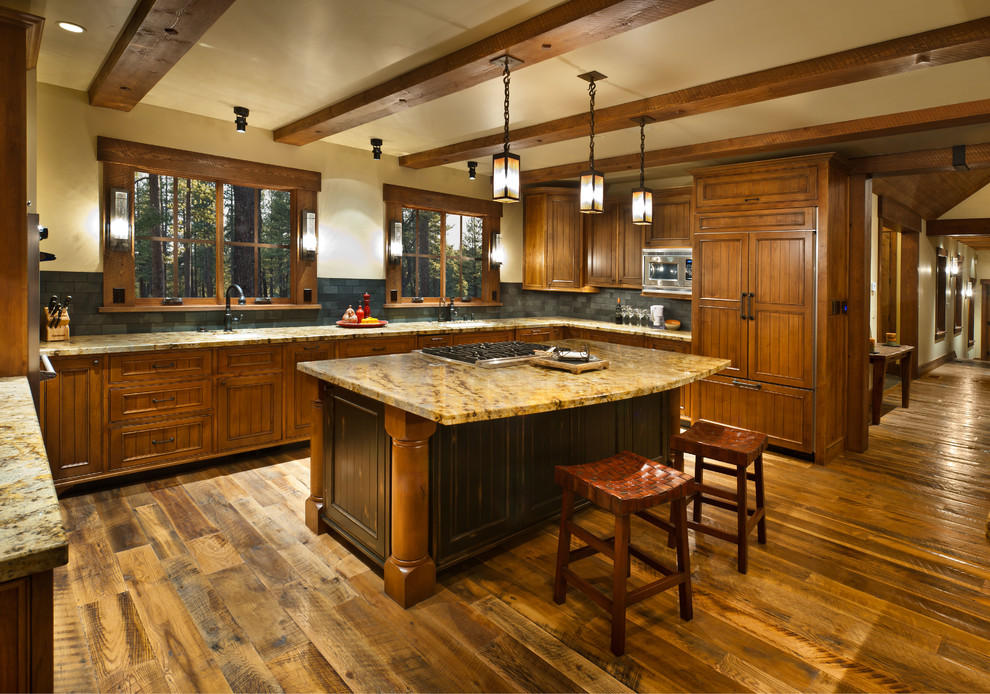 Rustik inredning av ett u-kök, med luckor med infälld panel, skåp i mellenmörkt trä, integrerade vitvaror, mörkt trägolv, en köksö och brunt golv