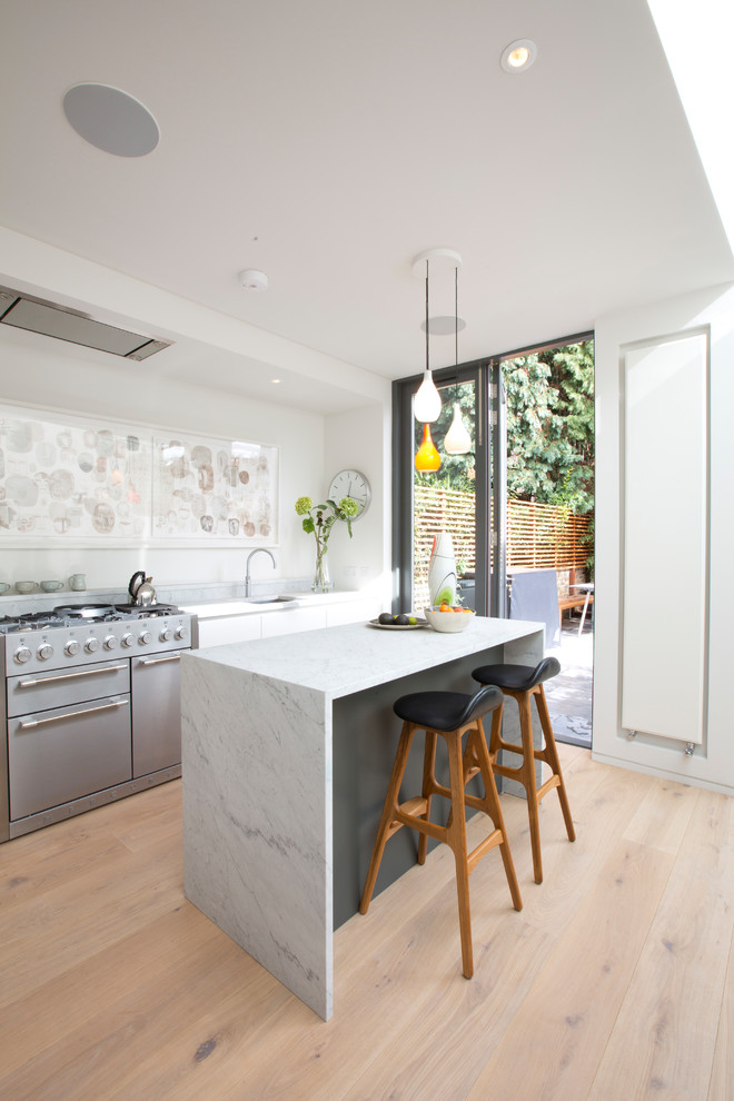 Inspiration för mellanstora moderna linjära vitt kök, med en undermonterad diskho, släta luckor, vita skåp, marmorbänkskiva, ljust trägolv, en köksö och beiget golv