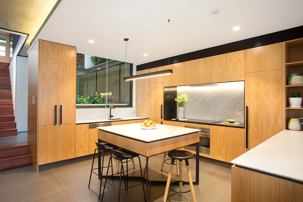 Large contemporary u-shaped open plan kitchen in Sydney with marble splashback, integrated appliances, an island, flat-panel cabinets, medium wood cabinets, white splashback, grey floors, a submerged sink, engineered stone countertops, porcelain flooring and white worktops.