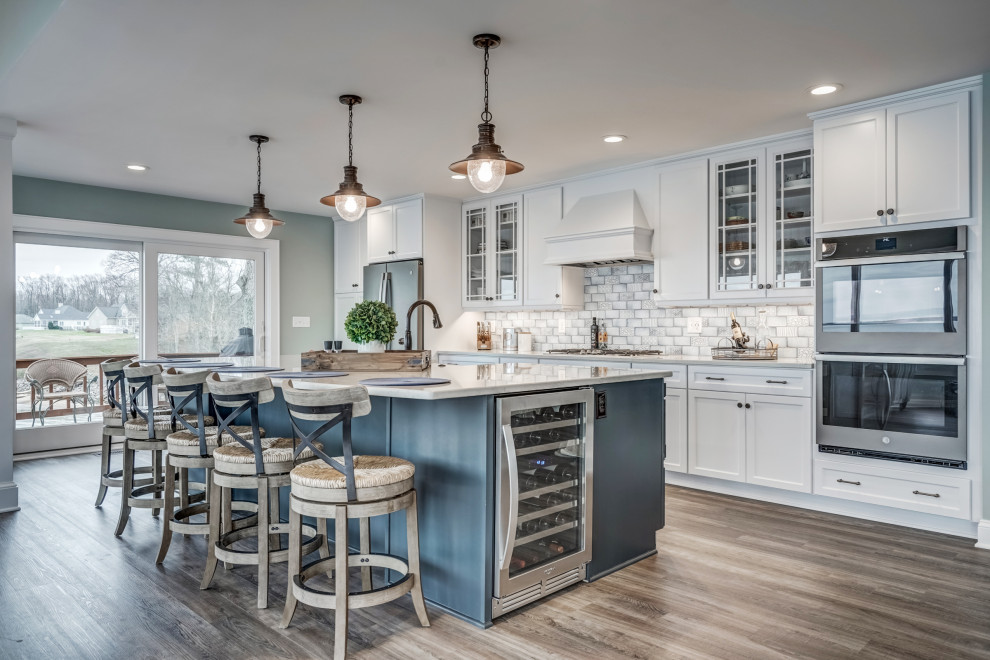 Immagine di una cucina costiera con ante in stile shaker, ante bianche, paraspruzzi grigio, elettrodomestici in acciaio inossidabile, parquet scuro, pavimento marrone e top grigio