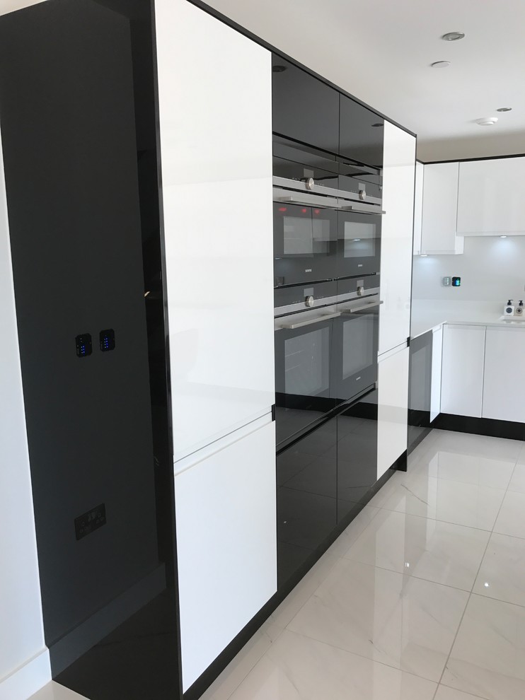 Inspiration for a large contemporary l-shaped open plan kitchen in Dorset with a built-in sink, flat-panel cabinets, white cabinets, quartz worktops, integrated appliances and an island.