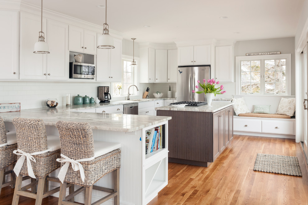 Design ideas for a beach style u-shaped kitchen in Boston with white cabinets, medium hardwood flooring and an island.