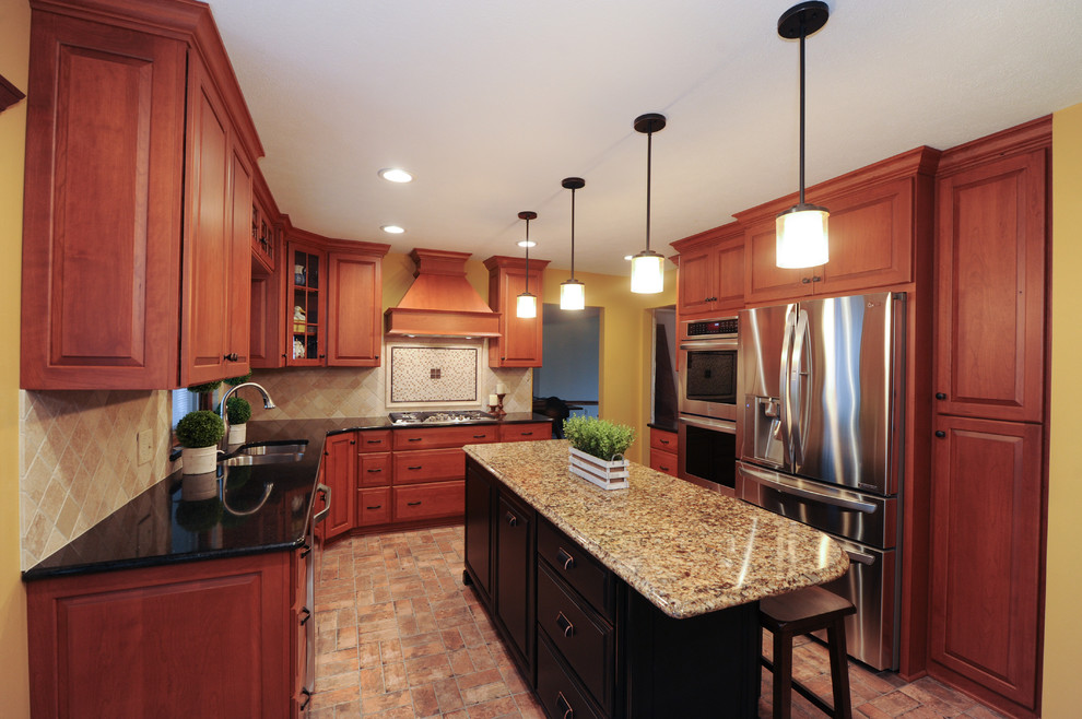 Exempel på ett stort klassiskt l-kök, med en undermonterad diskho, luckor med infälld panel, skåp i mellenmörkt trä, granitbänkskiva, stänkskydd i cementkakel, rostfria vitvaror, tegelgolv och en köksö