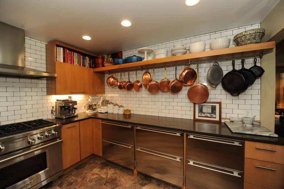 Bild på ett stort, avskilt industriellt kök, med en undermonterad diskho, släta luckor, skåp i mellenmörkt trä, granitbänkskiva, vitt stänkskydd, stänkskydd i tunnelbanekakel, rostfria vitvaror och en köksö