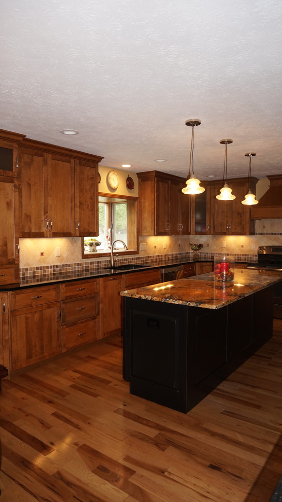 Große Rustikale Küche in L-Form mit Unterbauwaschbecken, Schrankfronten mit vertiefter Füllung, dunklen Holzschränken, Granit-Arbeitsplatte, braunem Holzboden und Kücheninsel in Cleveland
