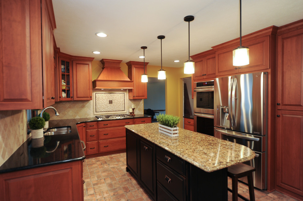 Example of a large classic l-shaped brick floor kitchen design in Cleveland with an undermount sink, recessed-panel cabinets, medium tone wood cabinets, granite countertops, cement tile backsplash, stainless steel appliances and an island