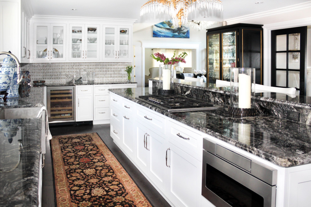 Classic l-shaped kitchen in Detroit with a belfast sink, glass-front cabinets, grey splashback, stainless steel appliances, an island, brown floors and black worktops.