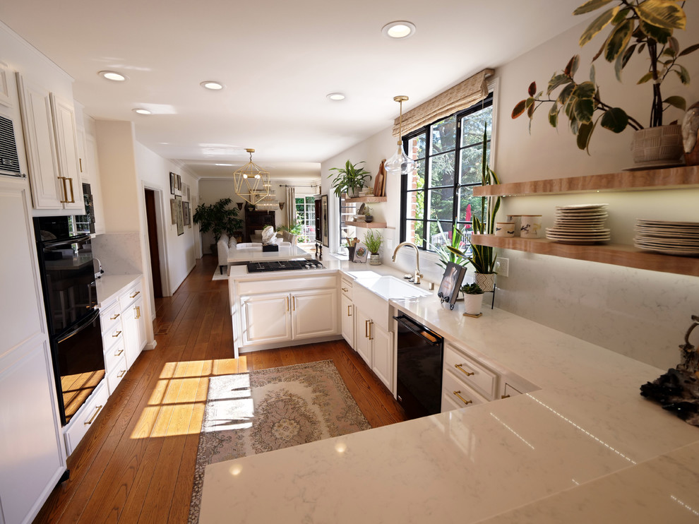 Example of a mid-sized trendy galley medium tone wood floor and brown floor eat-in kitchen design in San Francisco with a farmhouse sink, raised-panel cabinets, white cabinets, white backsplash, black appliances, an island, white countertops, quartzite countertops and stone slab backsplash