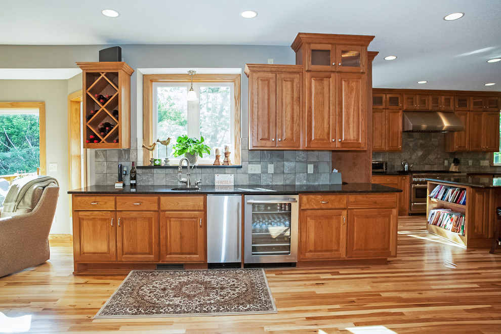 Example of a large classic galley open concept kitchen design in Minneapolis with raised-panel cabinets, medium tone wood cabinets, solid surface countertops, gray backsplash and cement tile backsplash