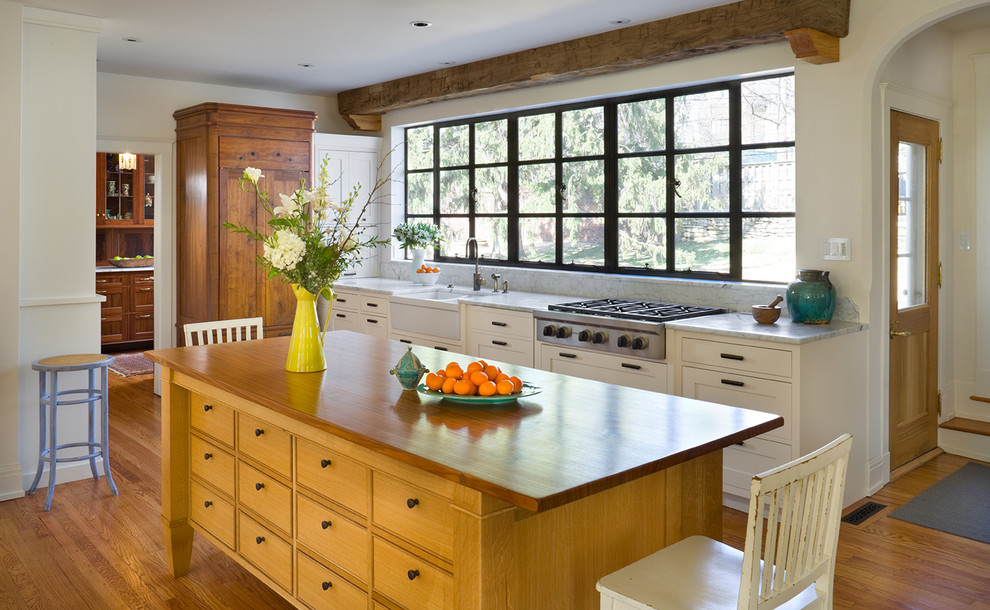 Klassische Küche in L-Form mit Landhausspüle, flächenbündigen Schrankfronten, weißen Schränken und Arbeitsplatte aus Holz in Kansas City