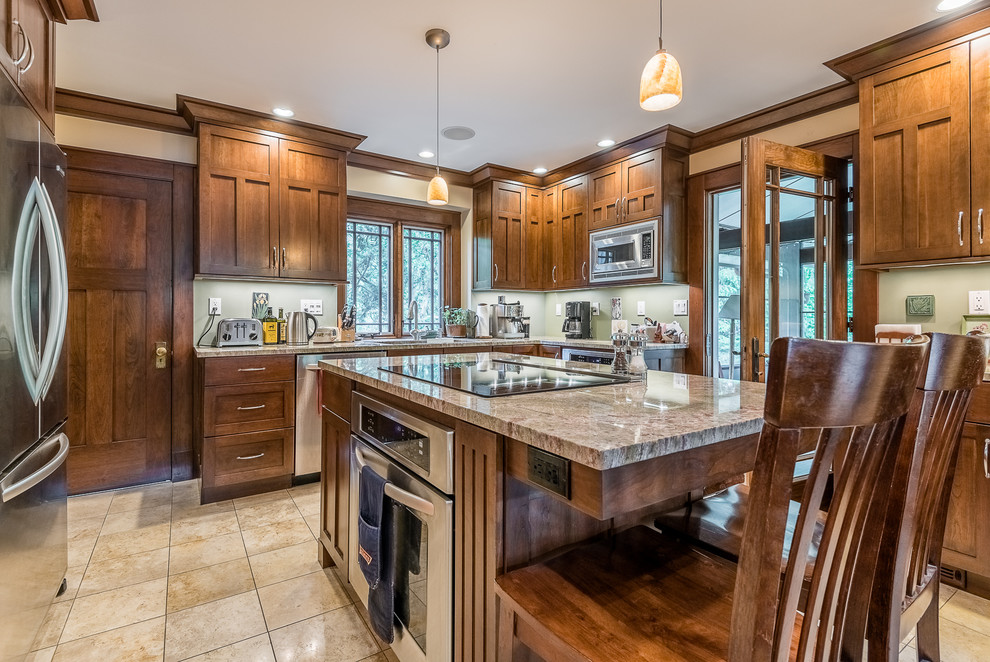 This is an example of a large classic u-shaped kitchen/diner in Chicago with a double-bowl sink, shaker cabinets, medium wood cabinets, granite worktops, green splashback, stainless steel appliances, ceramic flooring and multiple islands.