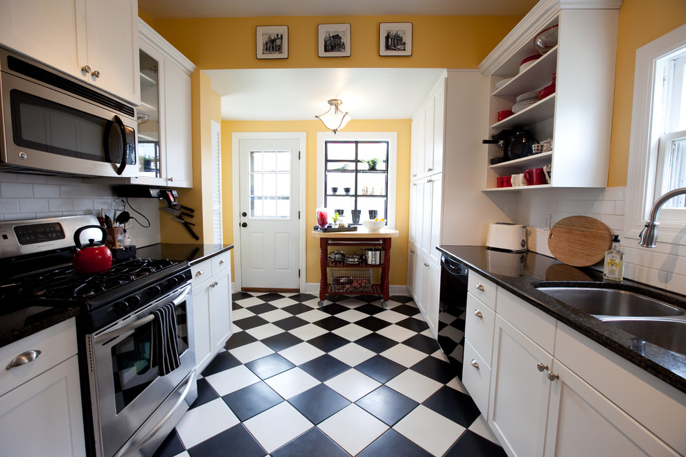Inredning av ett klassiskt avskilt kök, med en undermonterad diskho, skåp i shakerstil, vita skåp, vitt stänkskydd, stänkskydd i tunnelbanekakel, rostfria vitvaror och flerfärgat golv