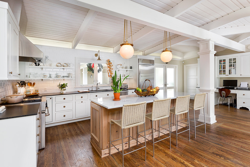 Photo of a rural kitchen in Miami with a submerged sink, shaker cabinets, white cabinets, white splashback, metro tiled splashback, stainless steel appliances, dark hardwood flooring and an island.