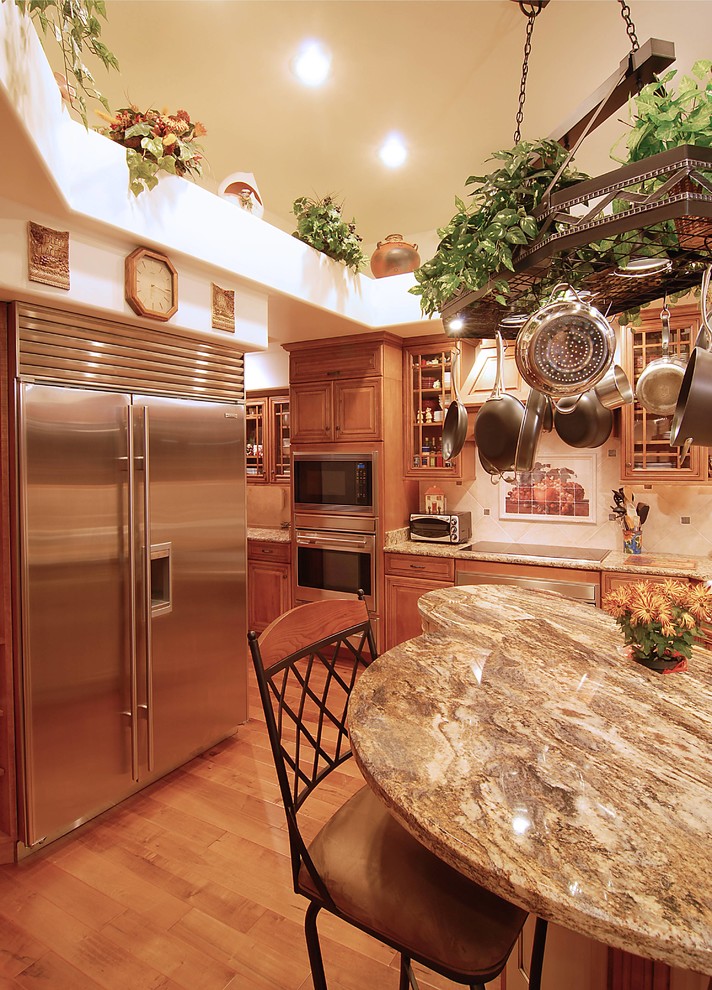 Exempel på ett stort medelhavsstil kök, med en rustik diskho, luckor med upphöjd panel, skåp i mellenmörkt trä, granitbänkskiva, vitt stänkskydd, stänkskydd i keramik, rostfria vitvaror, ljust trägolv och en köksö