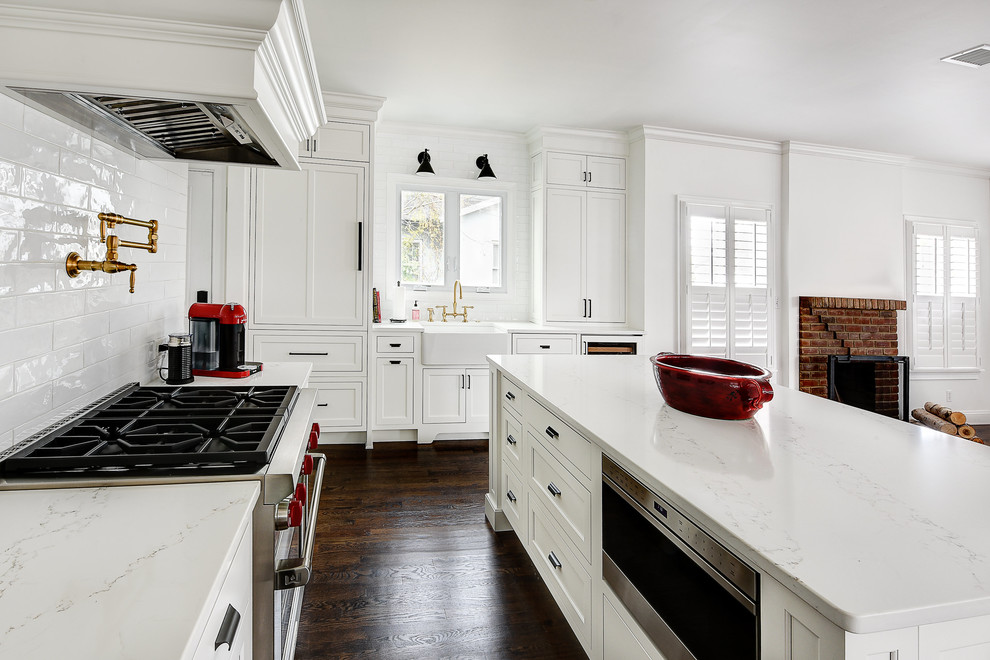 Eat-in kitchen - large transitional l-shaped dark wood floor and brown floor eat-in kitchen idea in Jacksonville with a farmhouse sink, white cabinets, quartz countertops, white backsplash, ceramic backsplash, an island, shaker cabinets, paneled appliances and white countertops