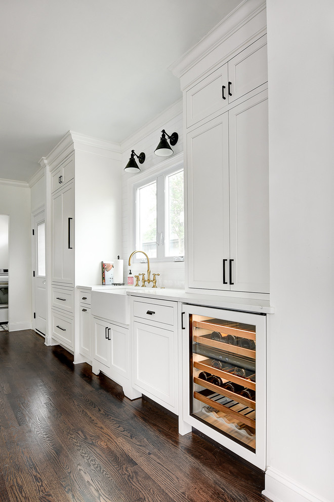 Eat-in kitchen - small transitional galley dark wood floor eat-in kitchen idea in Jacksonville with a farmhouse sink, recessed-panel cabinets, white cabinets, quartz countertops, white backsplash, ceramic backsplash, an island, white countertops and paneled appliances