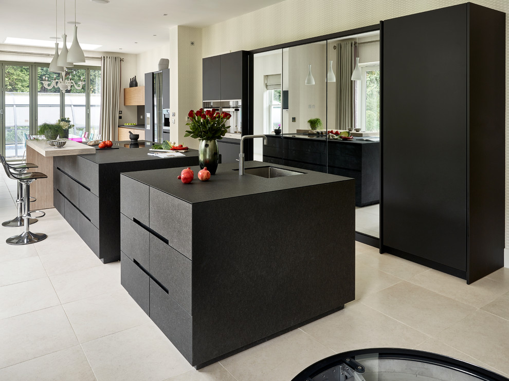 Contemporary kitchen in Surrey with a submerged sink, flat-panel cabinets, black cabinets, black appliances and multiple islands.