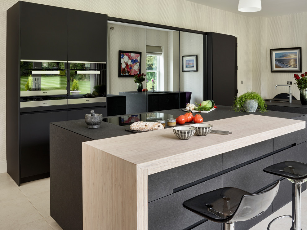 Diseño de cocina contemporánea con fregadero bajoencimera, armarios con paneles lisos, puertas de armario negras, electrodomésticos negros y dos o más islas