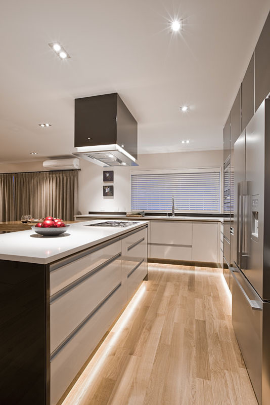 Immagine di una grande cucina design con lavello sottopiano, ante lisce, ante marroni, elettrodomestici in acciaio inossidabile e parquet chiaro