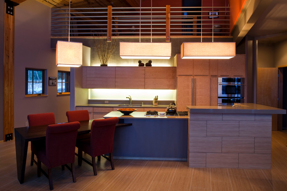 Example of a large trendy galley light wood floor eat-in kitchen design in Denver with a drop-in sink, flat-panel cabinets, light wood cabinets, wood countertops, beige backsplash, paneled appliances and an island