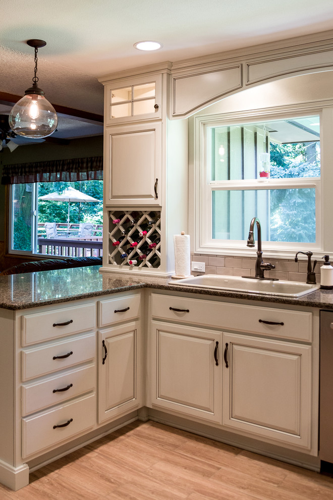 Inspiration for a mid-sized timeless u-shaped light wood floor and beige floor eat-in kitchen remodel in Portland with a drop-in sink, raised-panel cabinets, gray cabinets, granite countertops, gray backsplash, ceramic backsplash, stainless steel appliances and a peninsula
