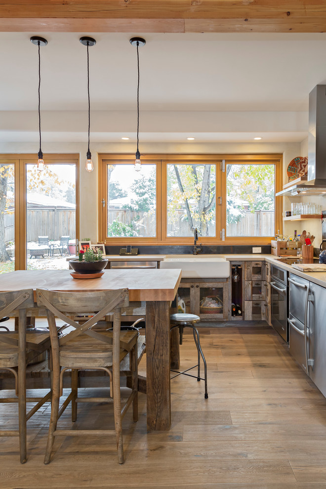 Medium sized farmhouse u-shaped kitchen/diner in Denver with a belfast sink, open cabinets, distressed cabinets, engineered stone countertops, metallic splashback, stainless steel appliances, light hardwood flooring, an island, beige floors and grey worktops.