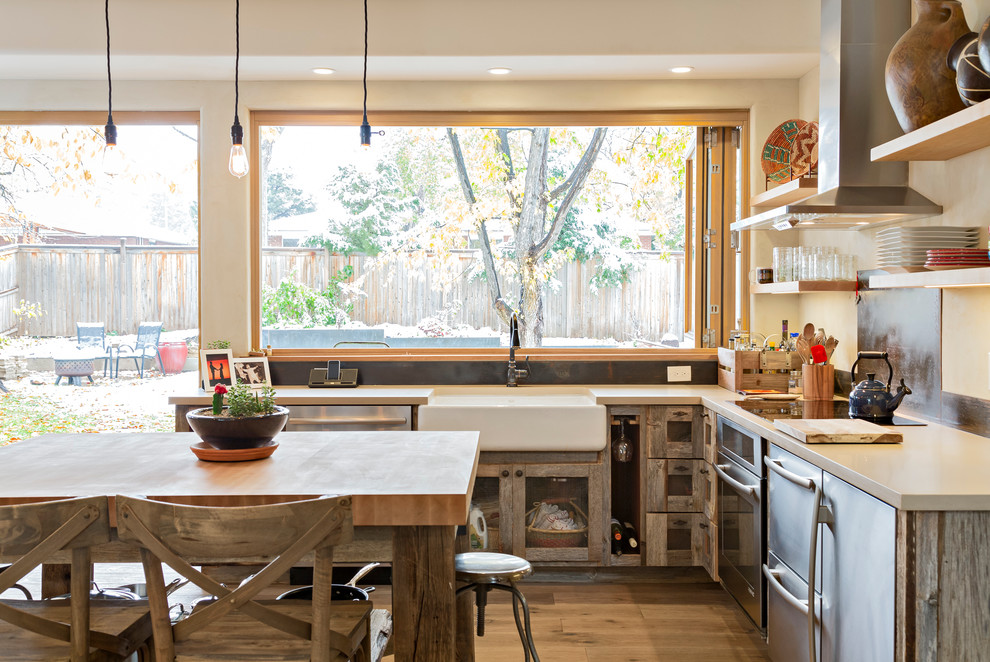 Example of a mid-sized southwest u-shaped light wood floor and beige floor eat-in kitchen design in Denver with a farmhouse sink, open cabinets, distressed cabinets, quartz countertops, metallic backsplash, stainless steel appliances, an island and gray countertops