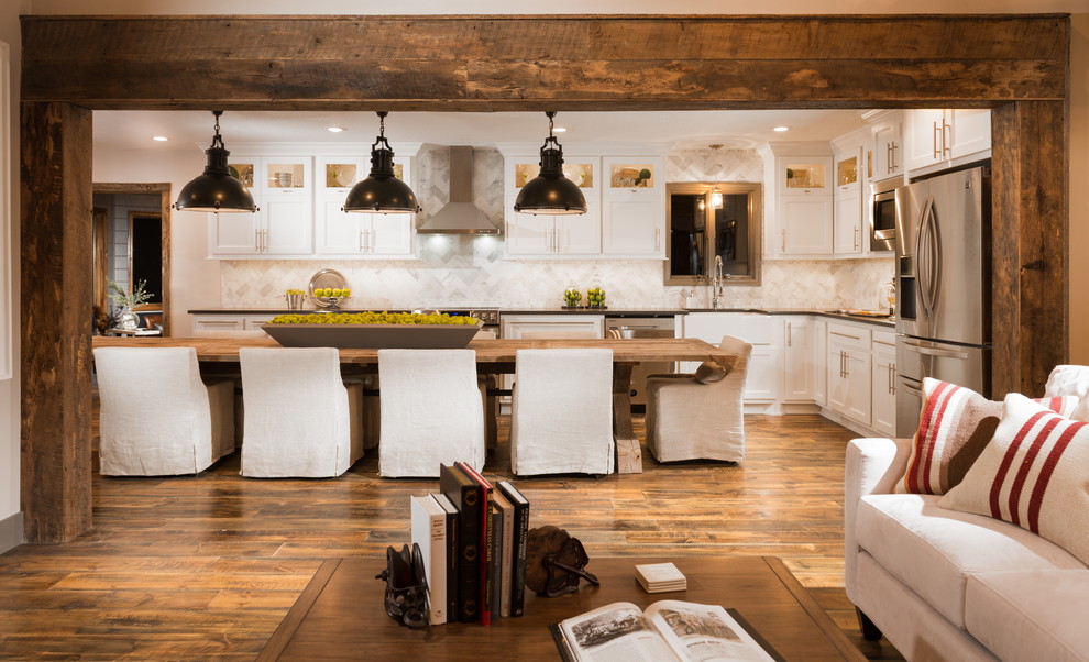 Rustik inredning av ett stort kök, med en rustik diskho, skåp i shakerstil, vita skåp, bänkskiva i kvartsit, vitt stänkskydd, stänkskydd i stenkakel, rostfria vitvaror, mellanmörkt trägolv, en köksö och brunt golv