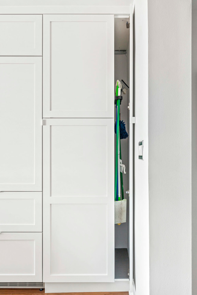 Cette photo montre une arrière-cuisine parallèle chic de taille moyenne avec un placard à porte shaker, des portes de placard blanches et une péninsule.