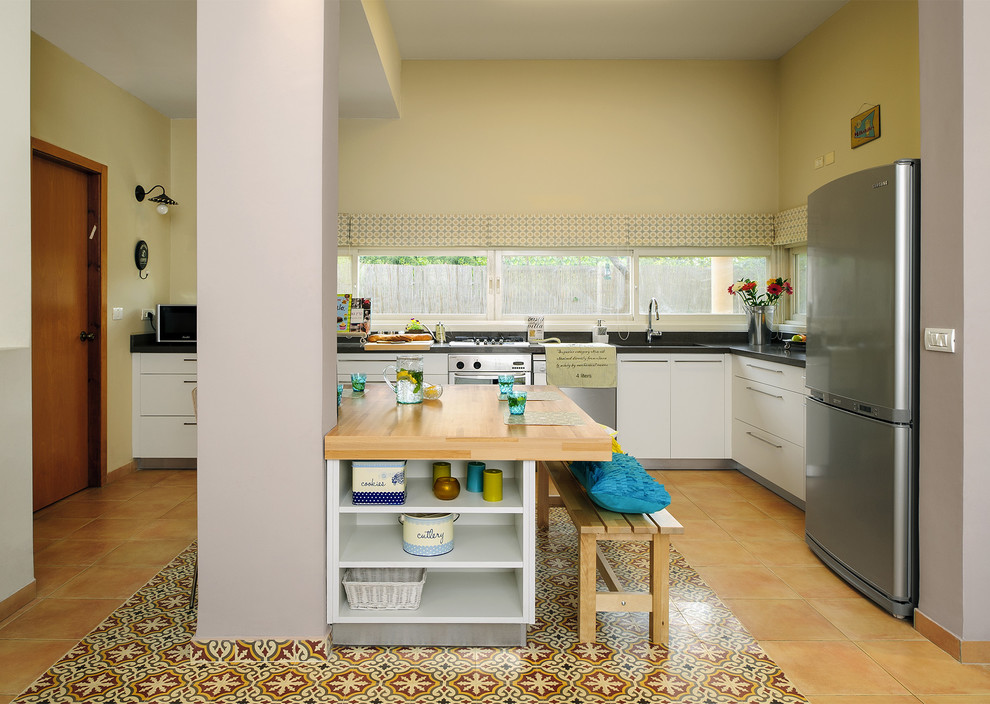 Moderne Küche in L-Form mit Küchengeräten aus Edelstahl, Arbeitsplatte aus Holz, flächenbündigen Schrankfronten und weißen Schränken in Tel Aviv